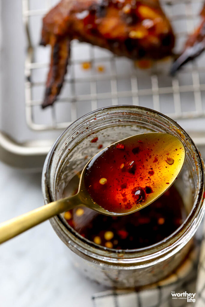 A spoonful of hot honey over a glass jar.