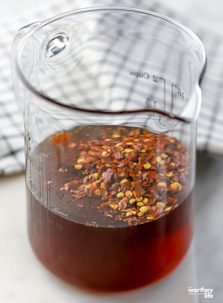 a glass measuring cup with honey and red pepper flakes. 