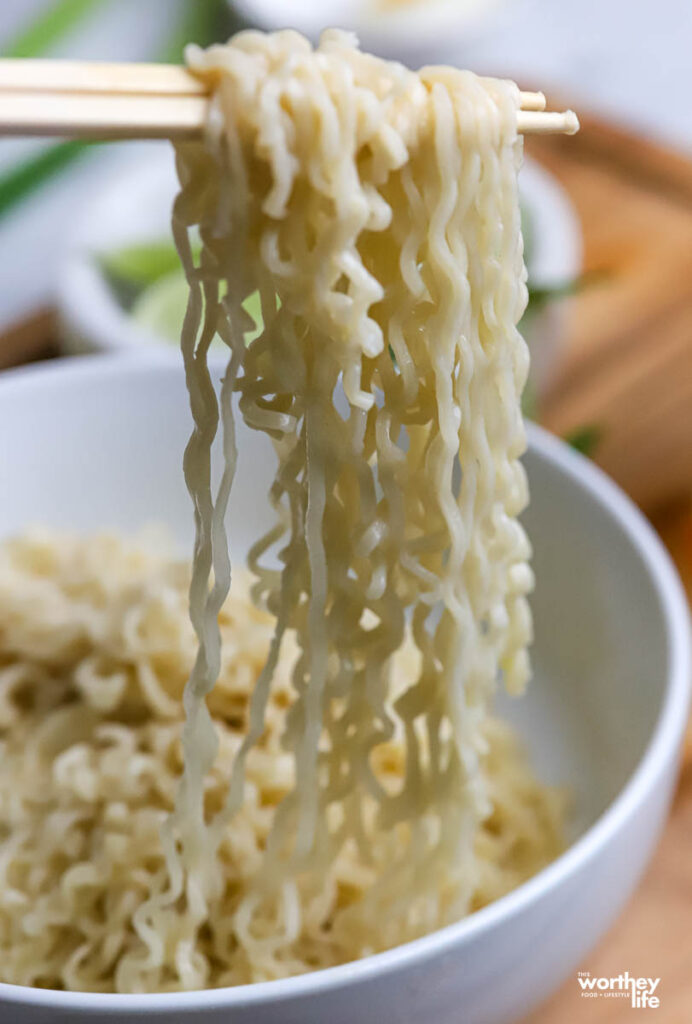 a white bowl of rice ramen with chopsticks. 