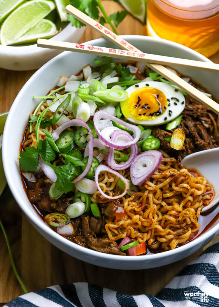 A bowl of Mexican pork birria ramen served in a white bowl. 