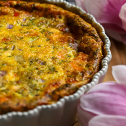 Salmon quiche in pie dish on counter with fresh flowers