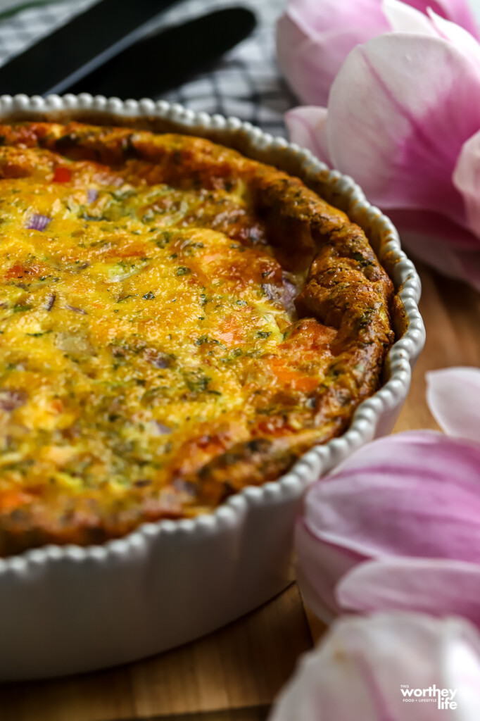 Salmon quiche in pie dish on counter with fresh flowers