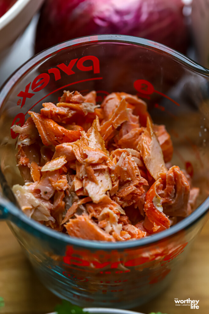 Chopped pieces of cooked salmon in a measuring cup