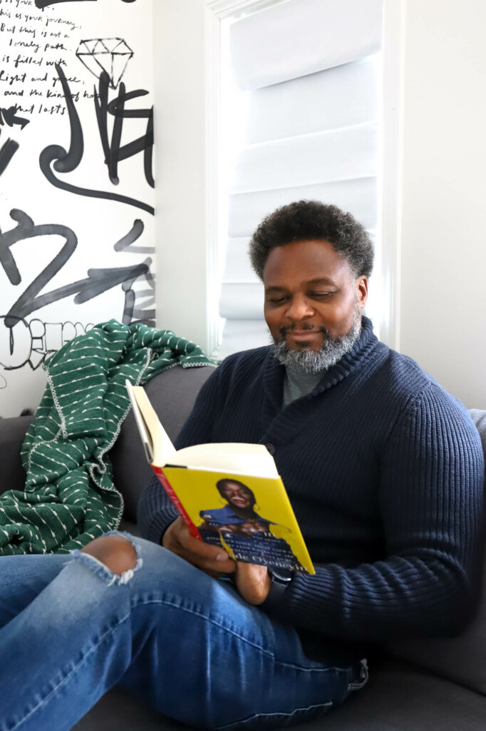 Derrick sitting on couch in the studio reading a book