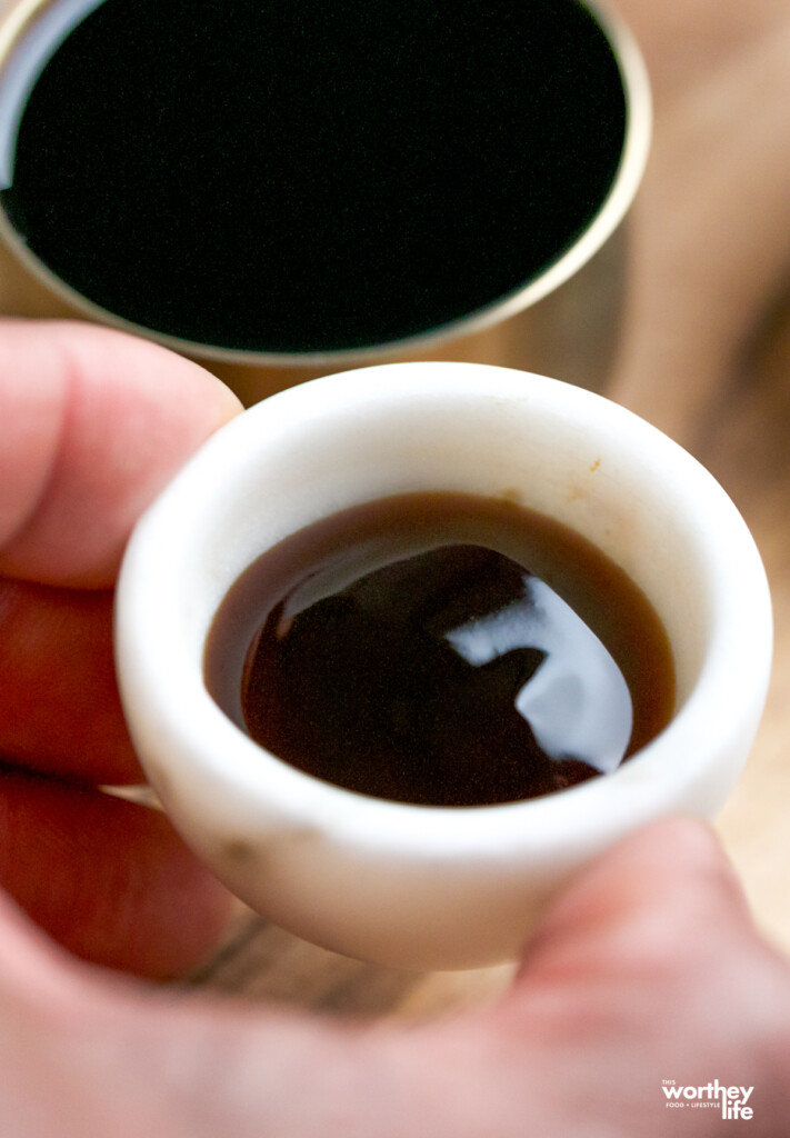 a man holding a little white marble bowl filled with soy sauce