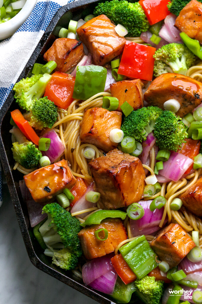 fresh salmon cubed into bite-sized pieces cooked in an air fryer paired with fresh vegetables and twirled pasta in a Finex skillet