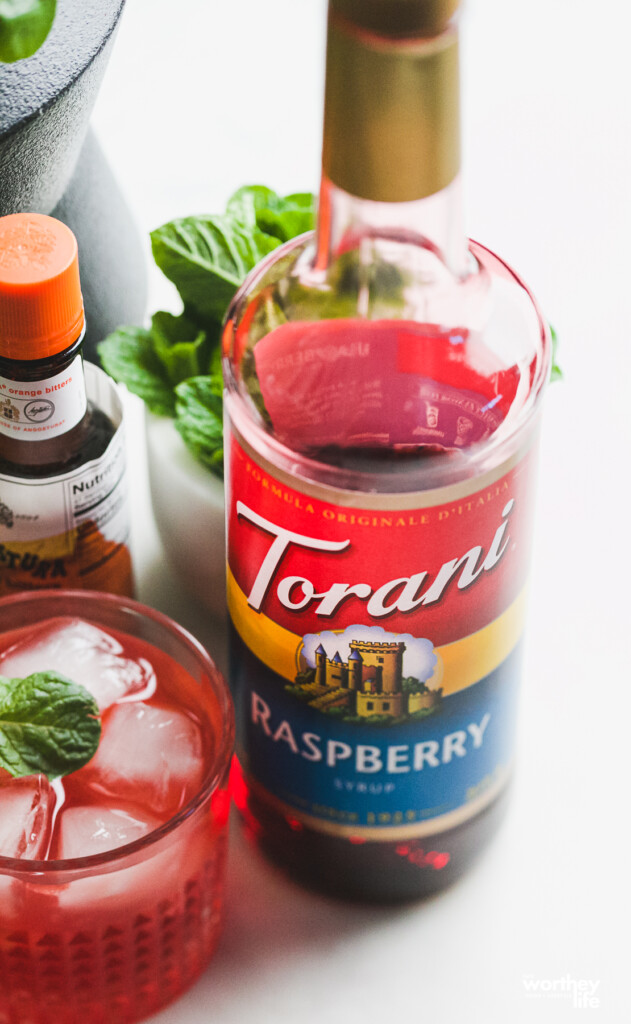 raspberry cocktail next to a bottle of Torani Raspberry syrup