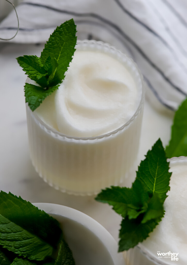 Frozen Coconut Margarita on a marble table with fresh garden mint. 