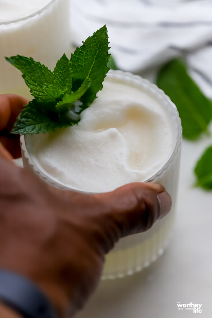 a hand grabbing a glass of frozen coconut margarita. 