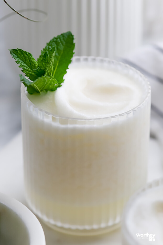 A glass filled with our frozen coconut margarita with fresh mint. 
