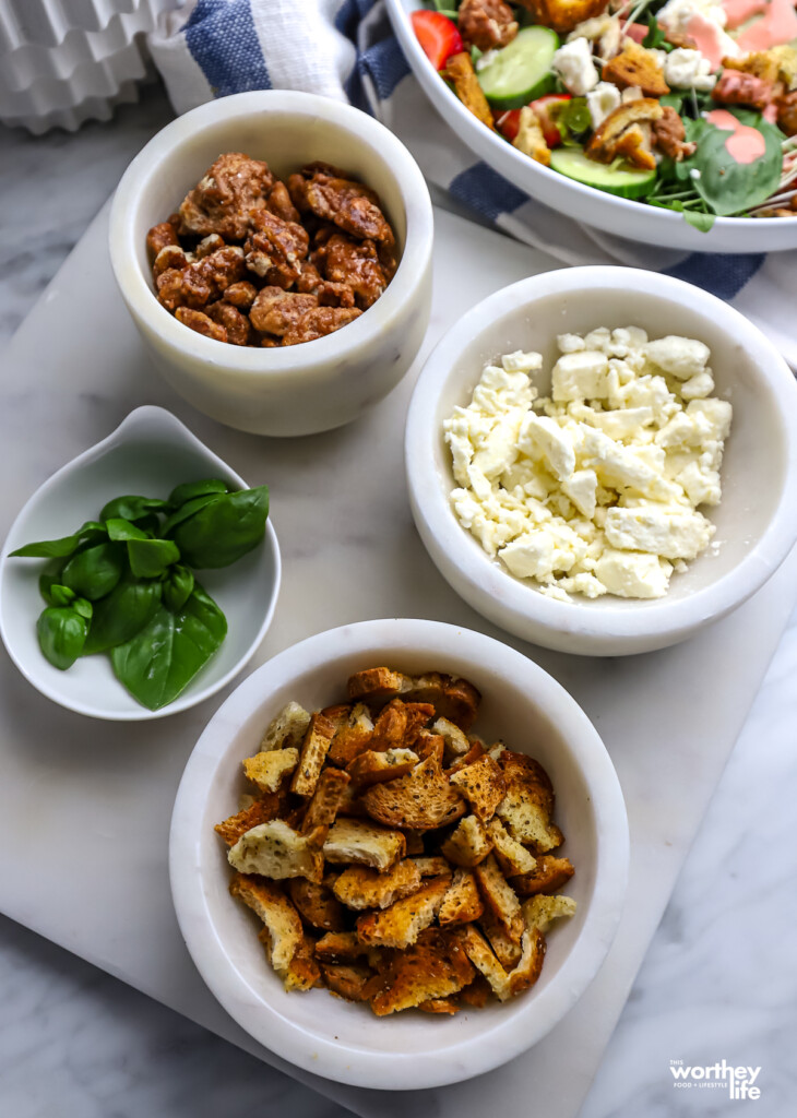 Salad and four white bowls of toppings. 