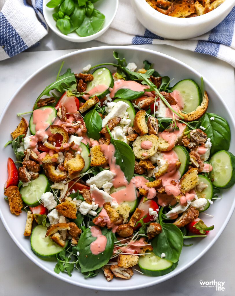 Strawberry Arugula Salad in a white salad bowl with homemade strawberry vinaigrette. 