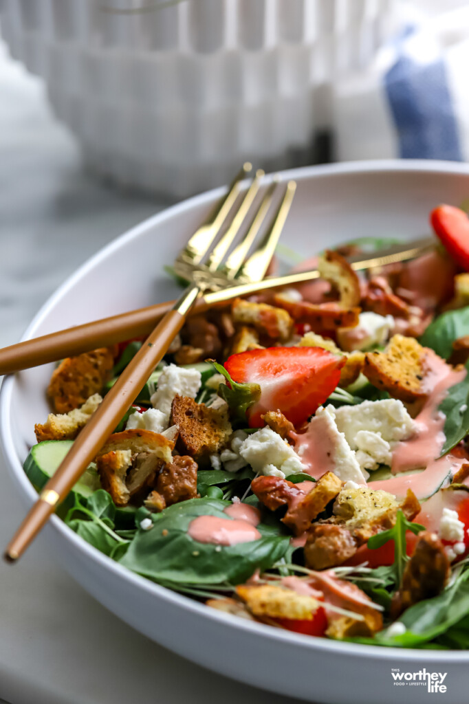 A partial view of our Arugula Strawberry Salad with a fork and knife. 