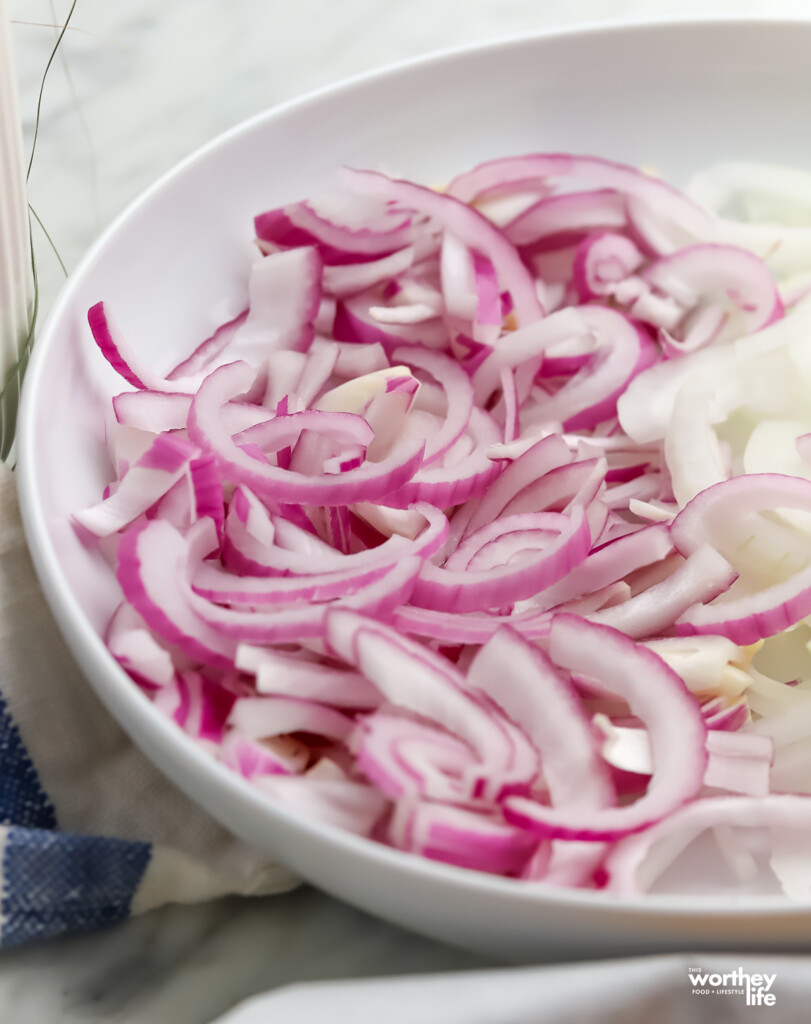 A bowl filled with thin sliced red onion. 