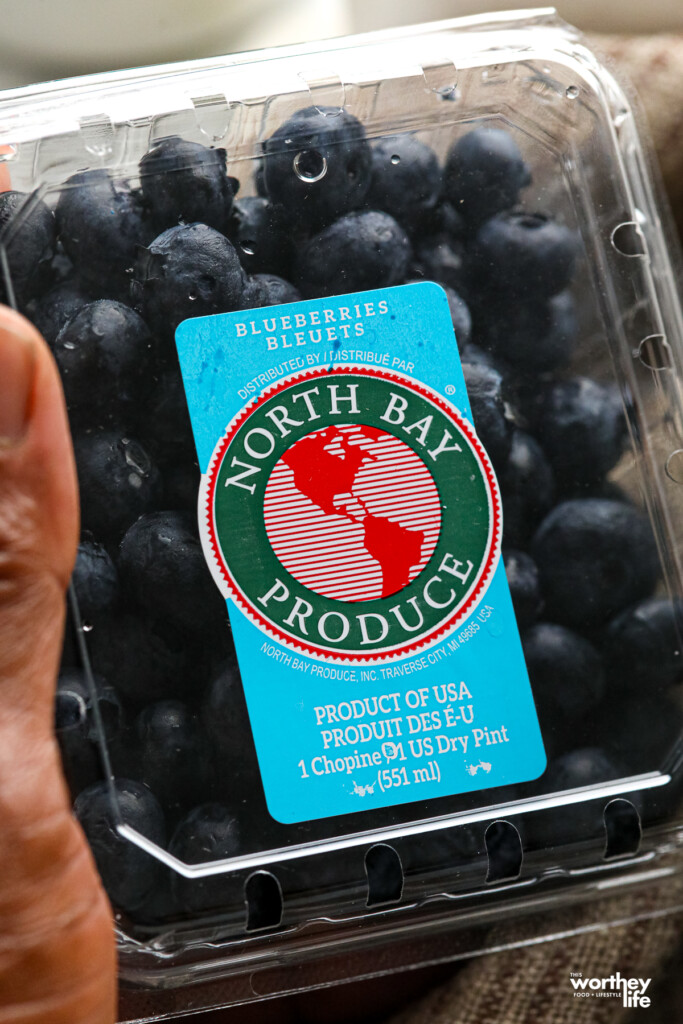 A hand holding a pint of North Bay Blueberries.