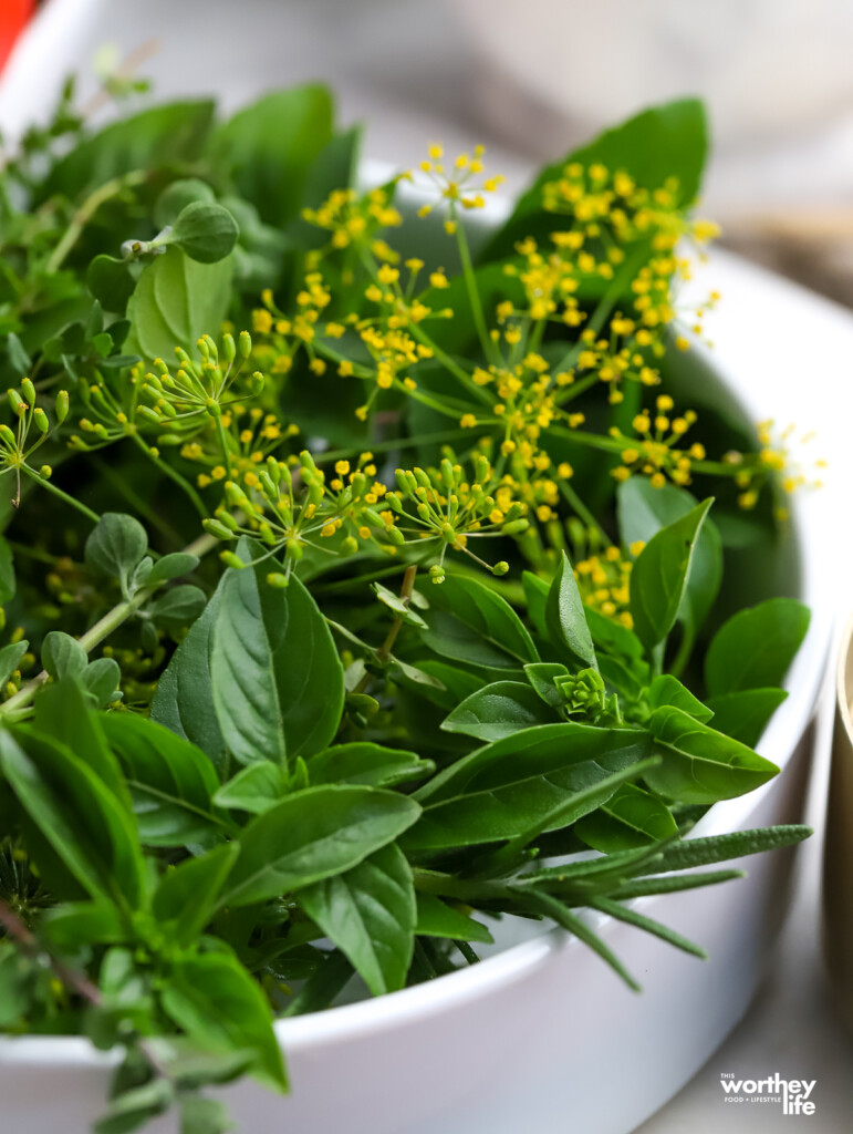 A white bowl filled with fresh herbs from the garden. 