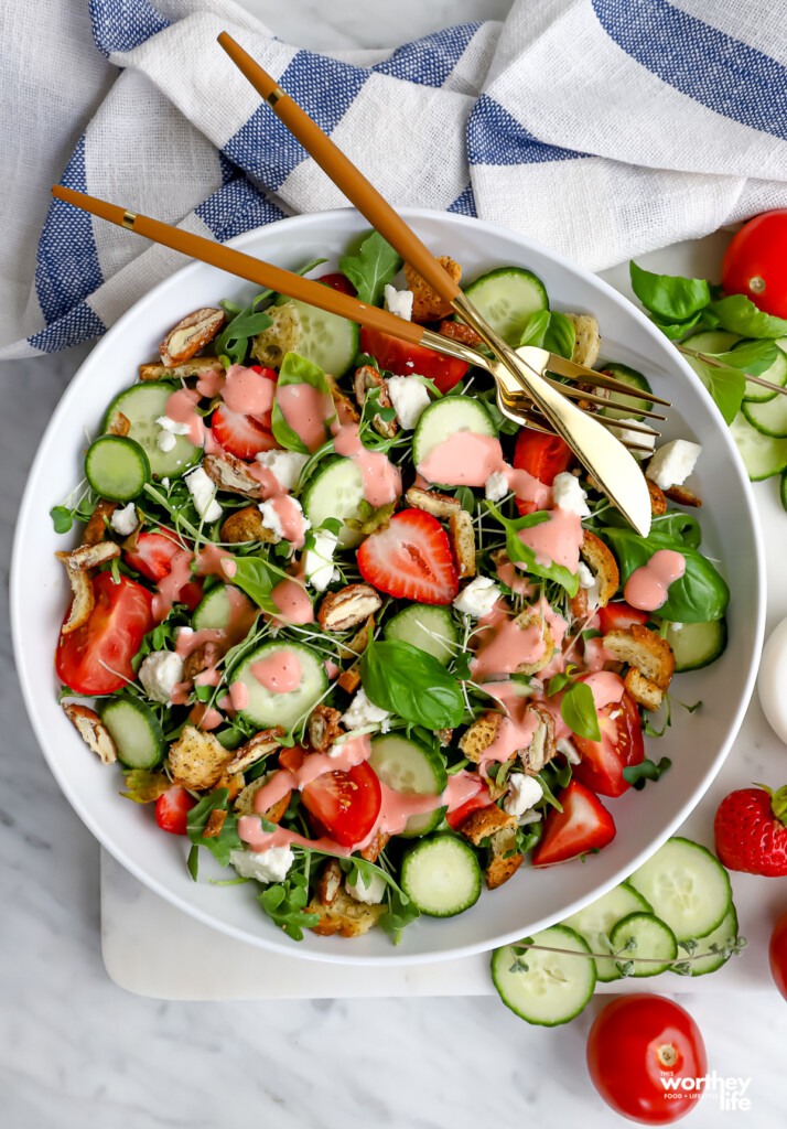 Strawberry Arugula Salad on white background with utensils and cloth napkin