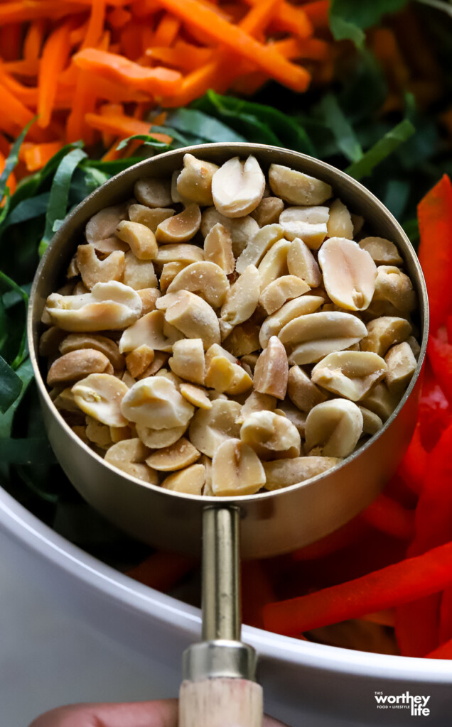 A measuring cup filled with chopped unsalted peanuts. 