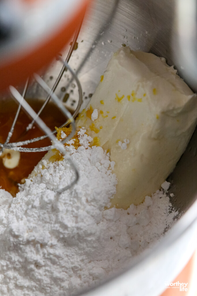 The ingredients for the cream cheese lemon icing in the bowl of a stand mixer. 