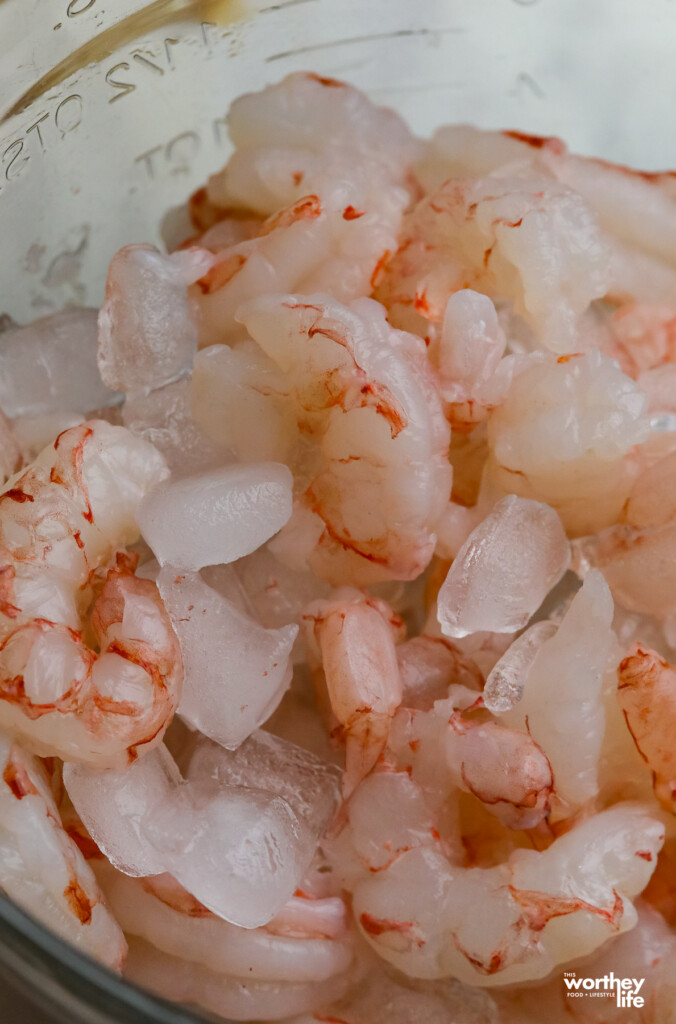 A large glass bowl filled with ice and shrimp.