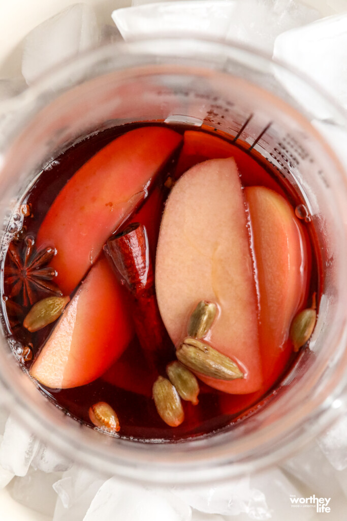  A clear glass measuring cup with slices of apple and spices. 