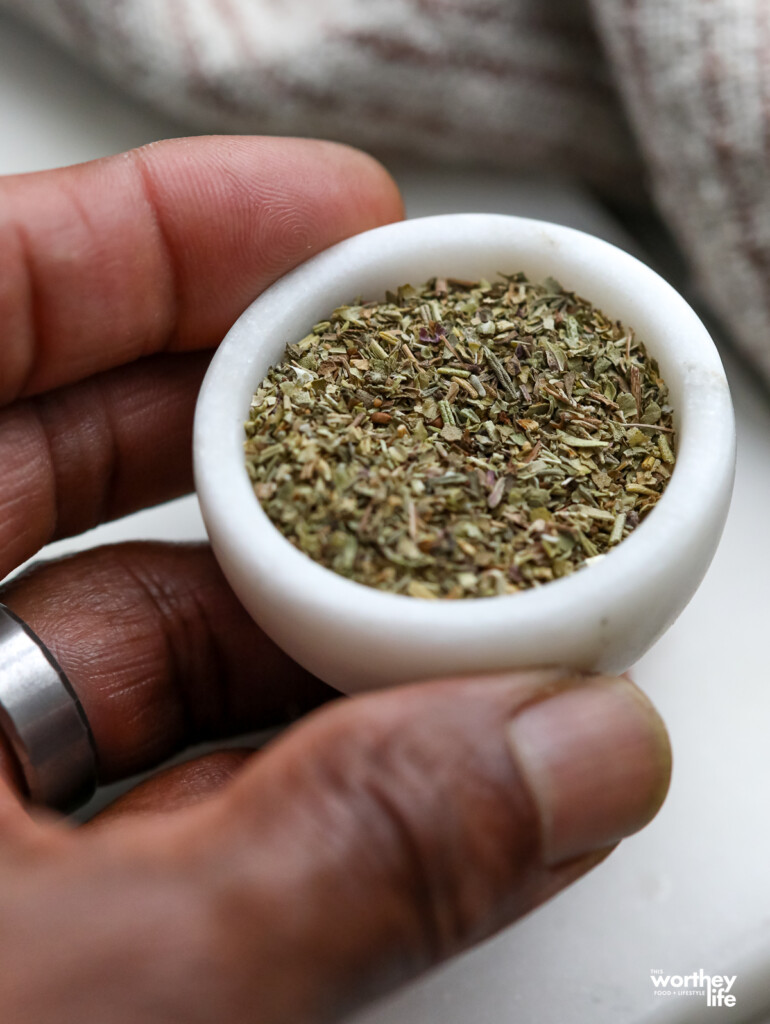 A small white marble bowl filled with Italian seasoning.