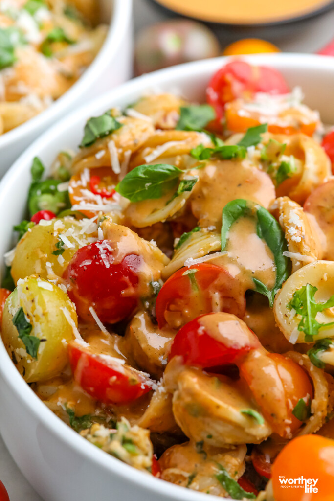 A side view of summer tomato pasta salad in a white salad bowl. 