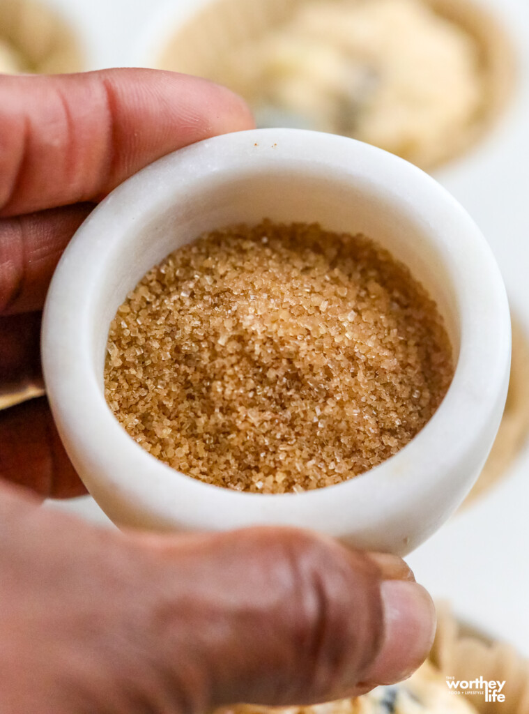A small white marbel bowl with raw sugar. 