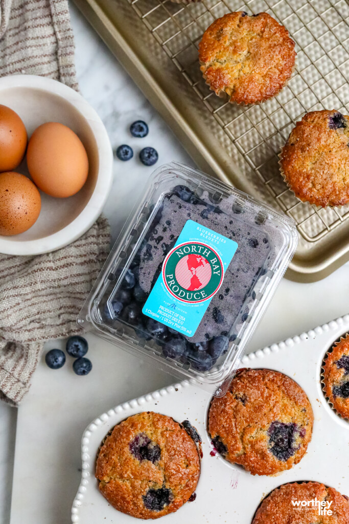 Muffins in a baking pan and North Bay Produce blueberries, and eggs.