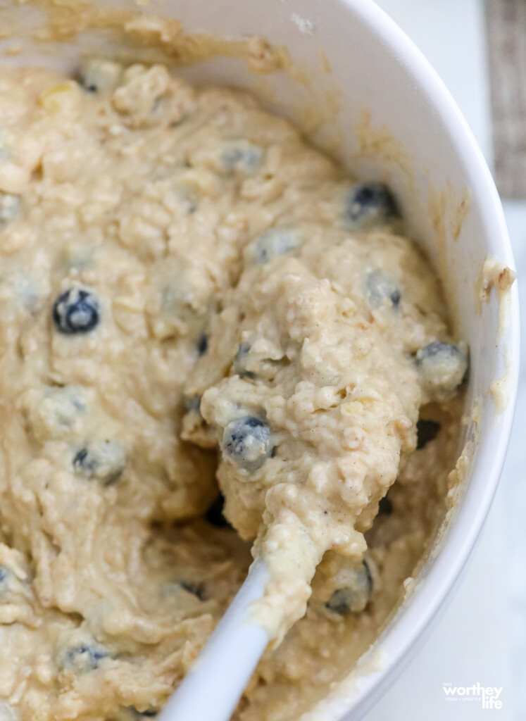 A large mixing bowl with mixed blue berry muffin batter. 
