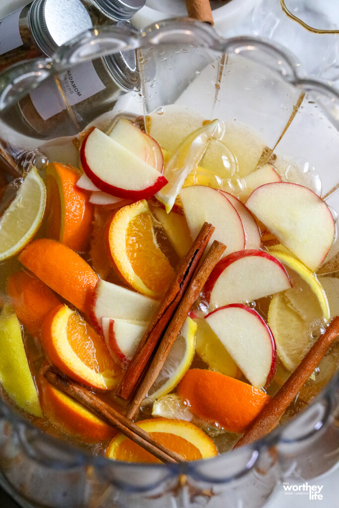 fresh sliced fruit in pumpkin punch bowl with cinnamon sticks