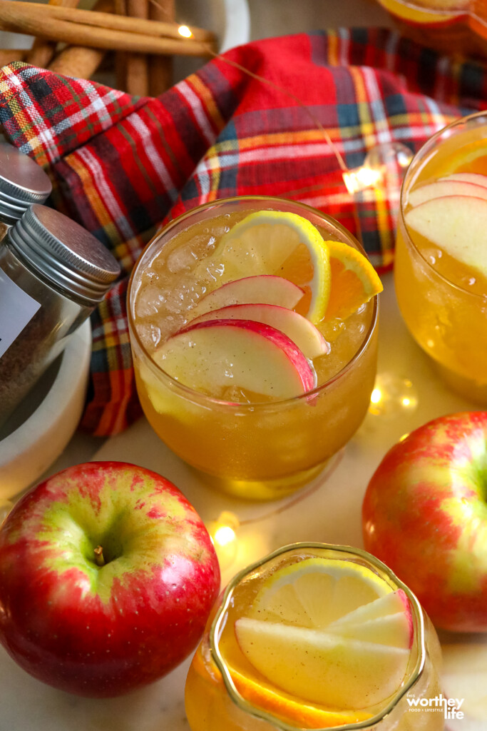 a cup of apple pie sangria in a glass with gold bottom and apples