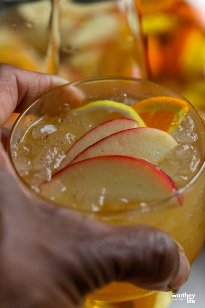 man holding a glass of apple cider sangria