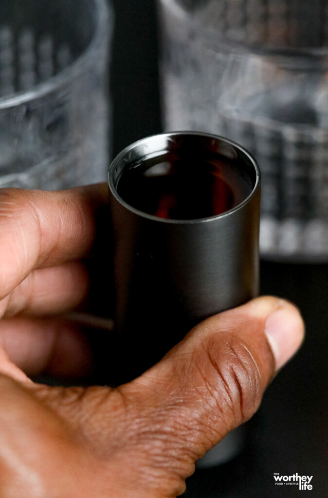 man holding a jigger filled with bourbon