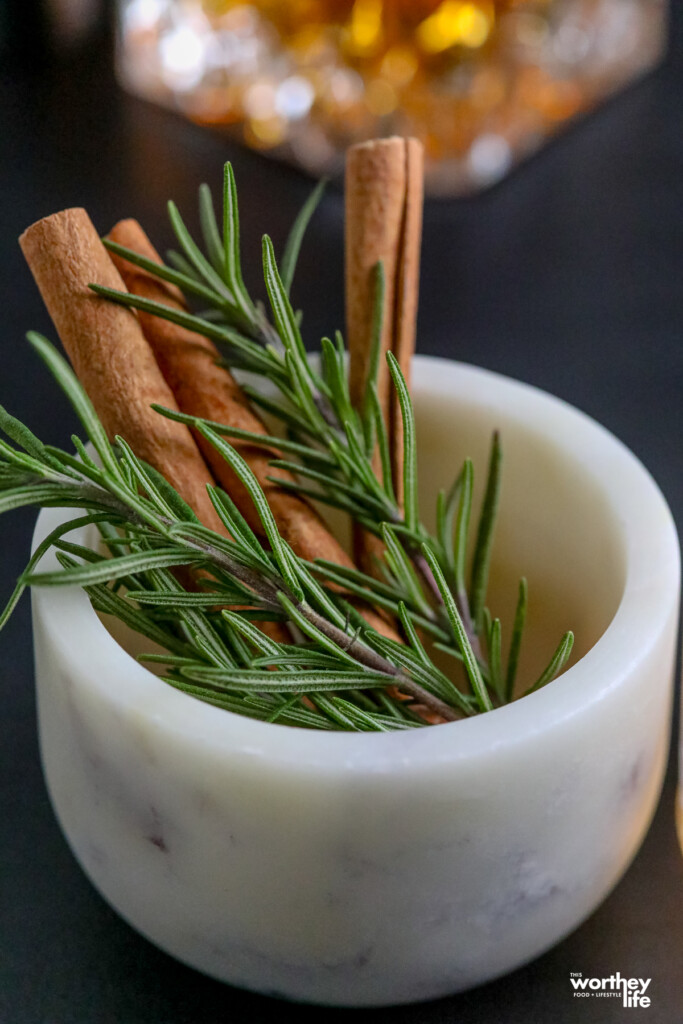 fresh herbs and cinnamon sticks in a white marble bowl