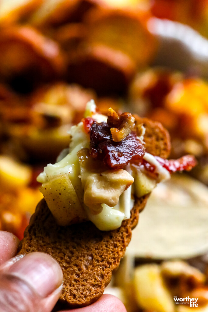 a man holding a portion of baked brie with bacon on lotus cookie