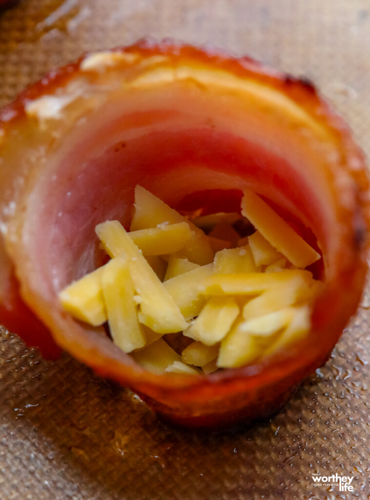 shredded cheese at the bottom of a bacon ring cup
