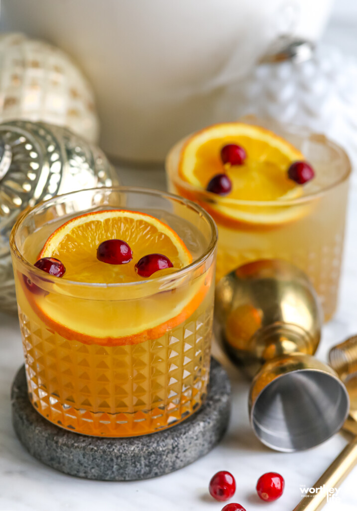 two glasses of a mocktail with gingerbread flavor, fresh cranberries and slices of orange