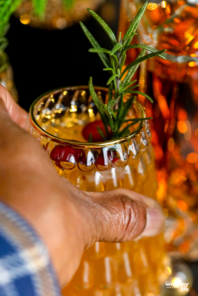 man holding a bourbon cocktail in a christmas tree glass