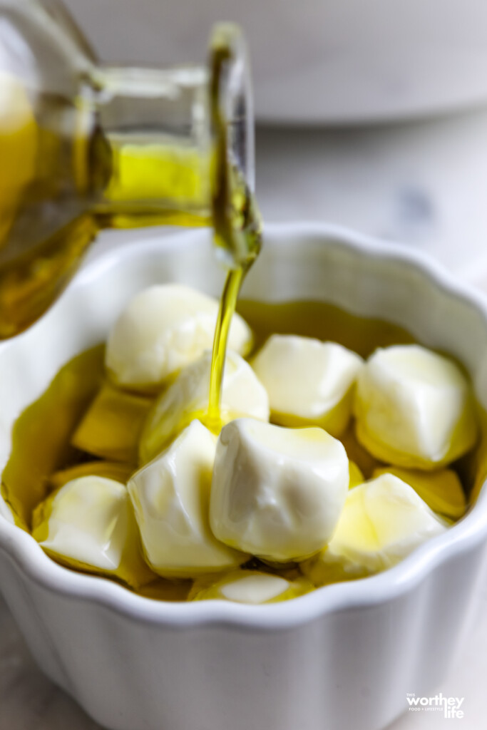drizzling olive oil over mozzarella balls