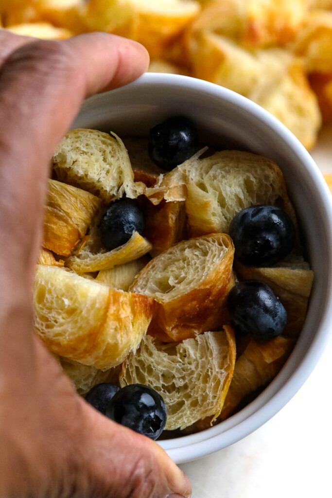 cubed croissants in white ramekin with blueberries