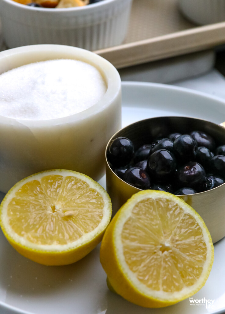 fresh blueberries in a measuring cup with a slice of lemon