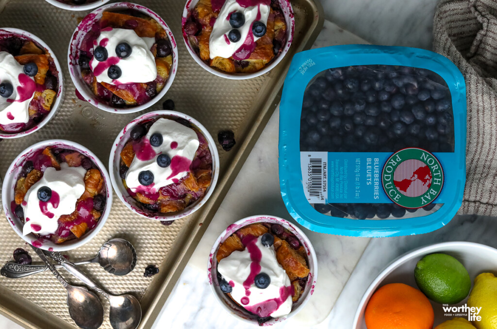 blueberry bake recipe in white ramekins on baking tray next to a package of fresh blueberries