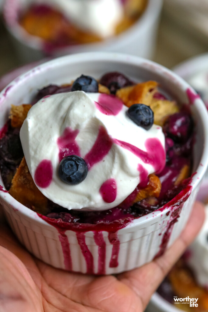 man holding a white ramekin filled with a blueberry breakfast bake