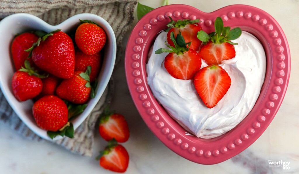 fresh strawberries in a heart shaped bowl next to strawberry fluff dip