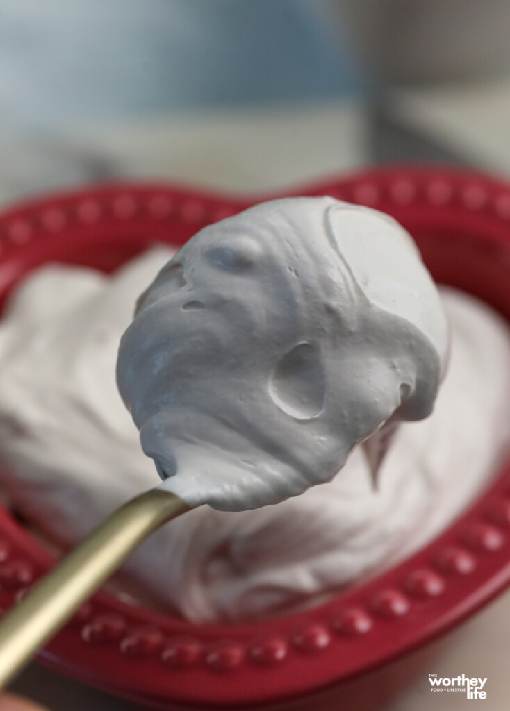 holding a spoon with fruit dip on it. 