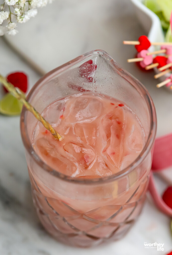 Our creamy raspberry cocktail in a crystal cocktail mixing glass with a gold long-handled bar spoon. 