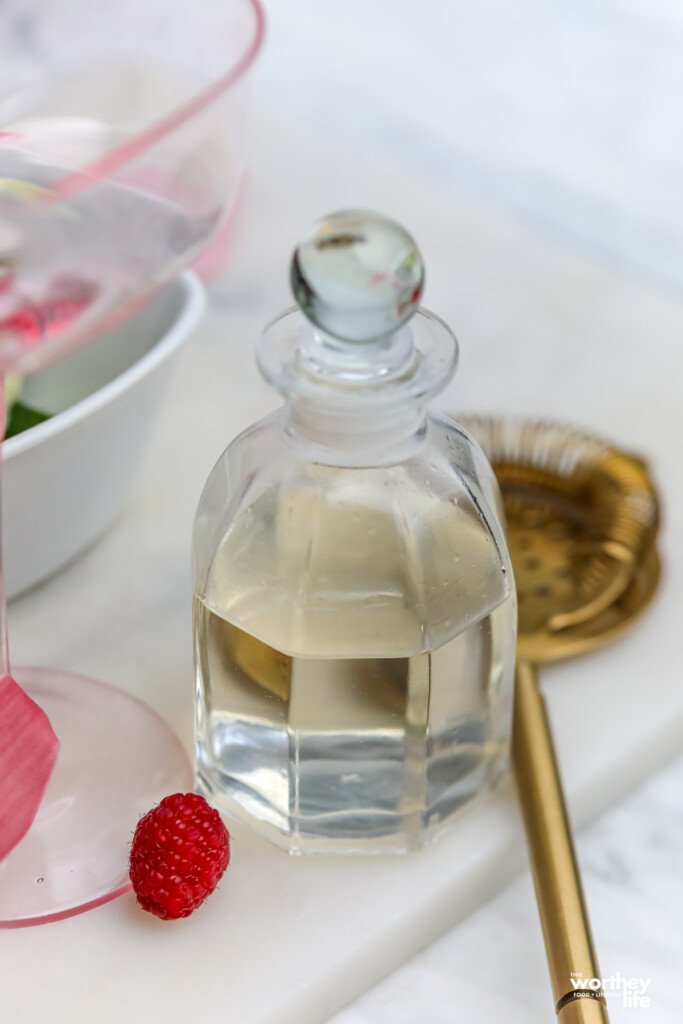 A bottle of somemade simpel syrup in a clear glass container with a bottle-stopper. 