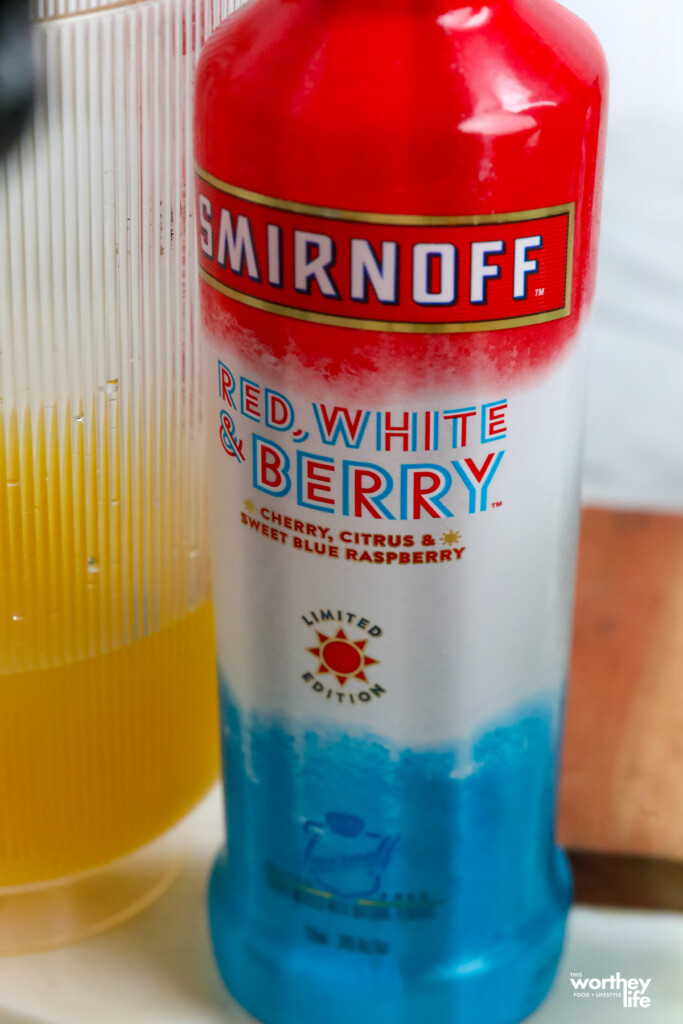 bottle of Smirnoff Red, White and Berry Vodka next to orange juice 