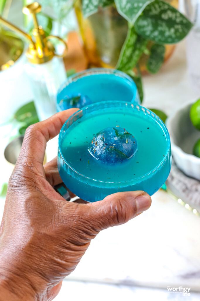 man holding a blue mocktail in his hand